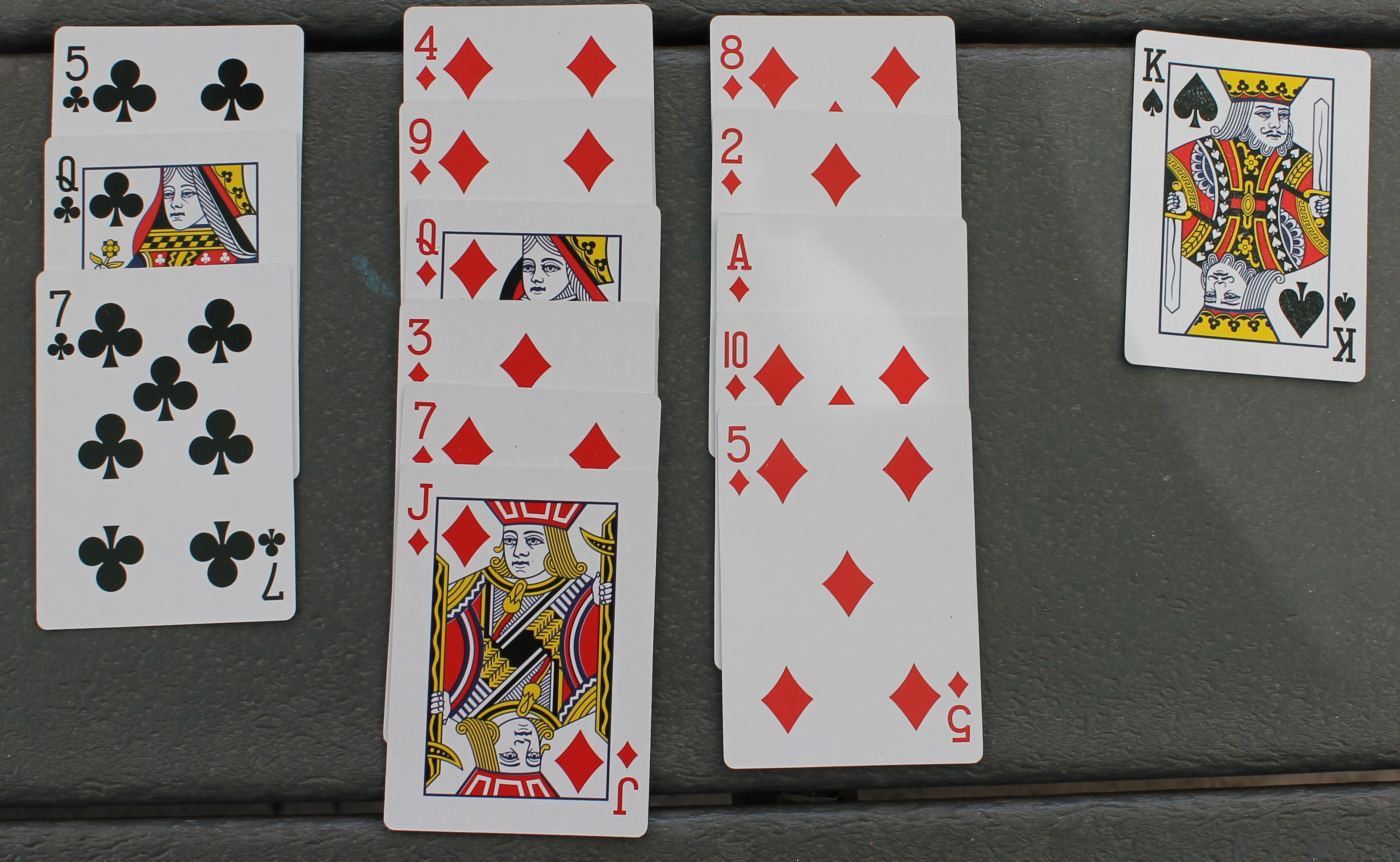 Fifteen playing cards, 3 clubs, 11 diamonds, one spade.