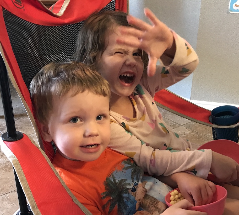 Two children in a chair eating cereal