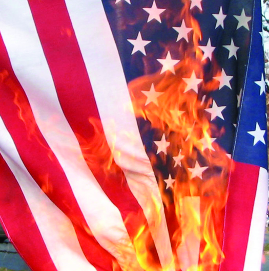 A photo of an American flag. The flag is on fire.