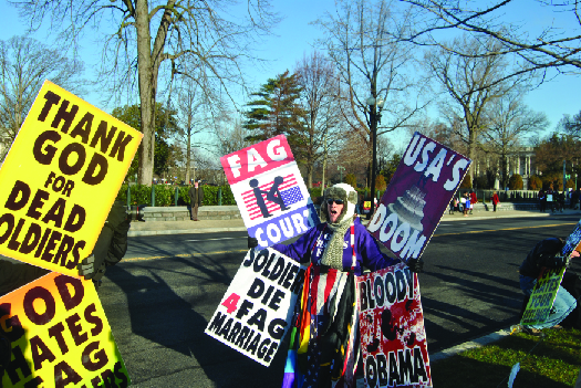 A photo of people holding signs. The signs read “Thank God for dead soldiers”, “God hates—”, “Fag Court”, “Soldiers die 4 fag marriage”, “USA’s doom,” and “Bloody Obama”.